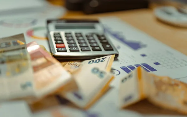 A calculator and banknotes on financial documents, representing how to use the Hibah calculator