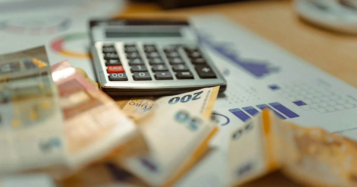 A calculator and banknotes on financial documents, representing how to use the Hibah calculator
