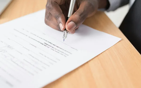 A hand signing a legal document, representing a living trust structure