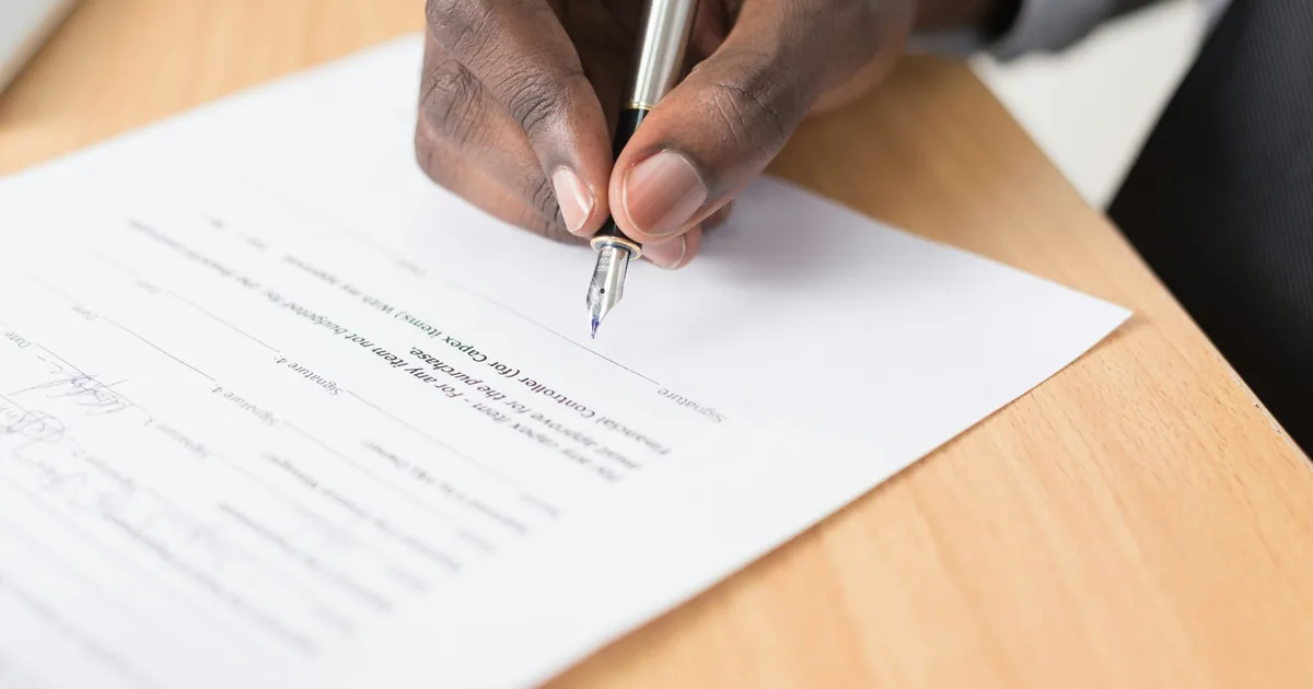 A hand signing a legal document, representing a living trust structure