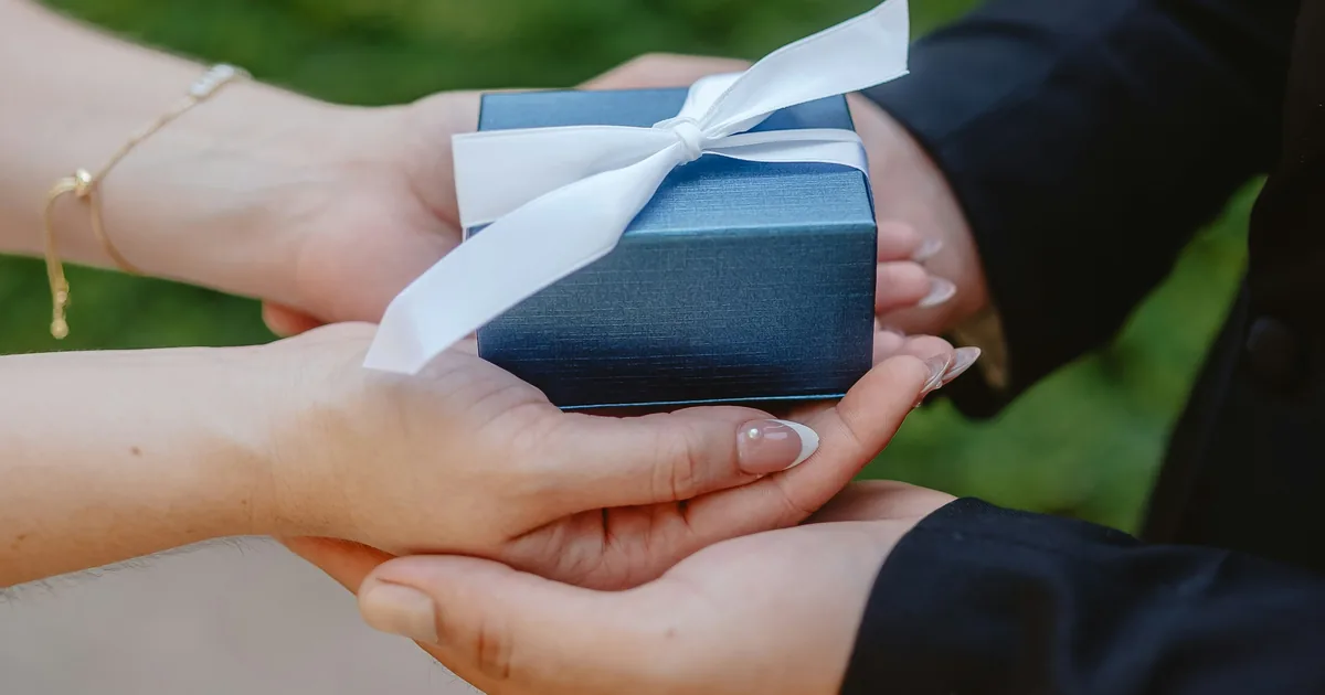 Hands exchanging a wrapped gift, representing Hibah, the Islamic lifetime gift