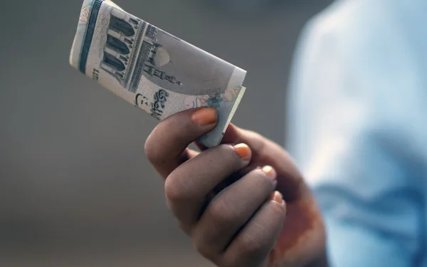 A hand holding folded banknotes, representing the Mahr a husband gives his wife
