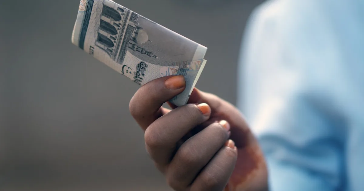 A hand holding folded banknotes, representing the Mahr a husband gives his wife