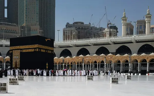 Pilgrims in Ihram and everyday dress walking near the Kaaba at Masjid al-Haram in Makkah